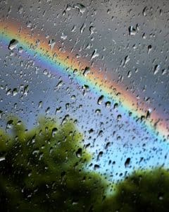 rain drops on a window with rainbow in sky